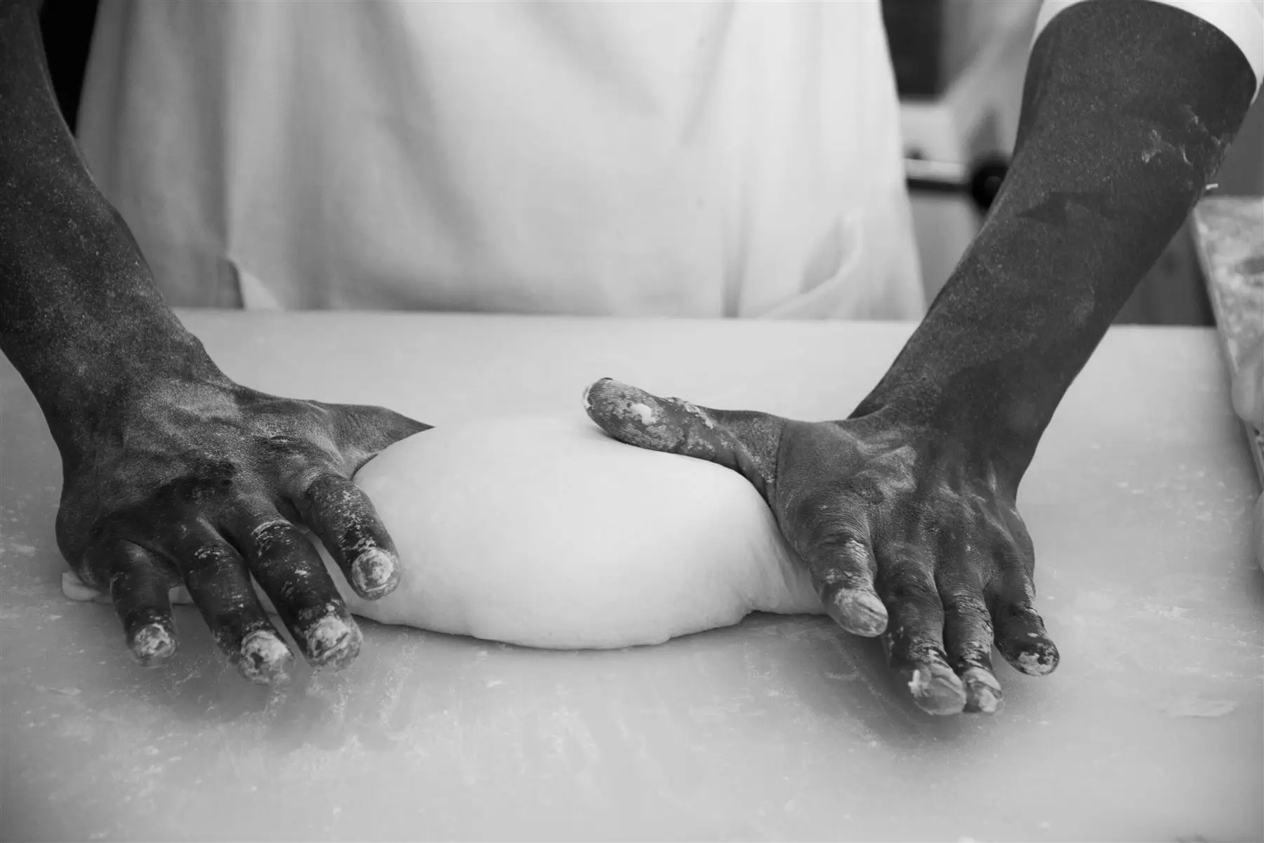Hands shaping sourdough by hand, in black and white