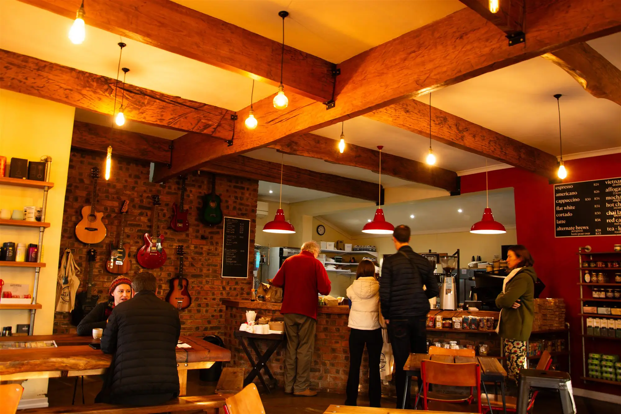 The Upper Millstone interior — warm pendant lighting, exposed timber beams, guitars on the wall and locals at the counter